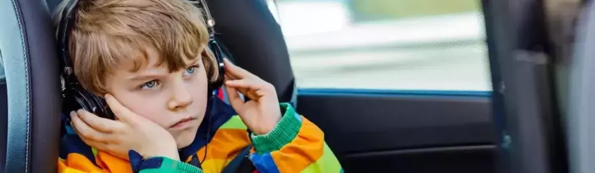 Niño pequeño escuchando música en el coche en la silla de niños