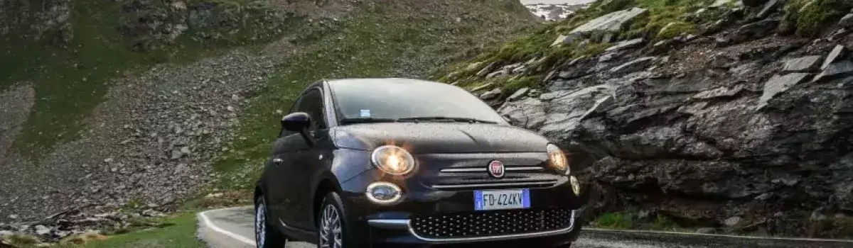 Fiat 500 negro en la carretera un día de lluvia