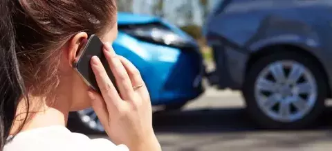 Mujer llamando para comunicar un coche entre dos coches
